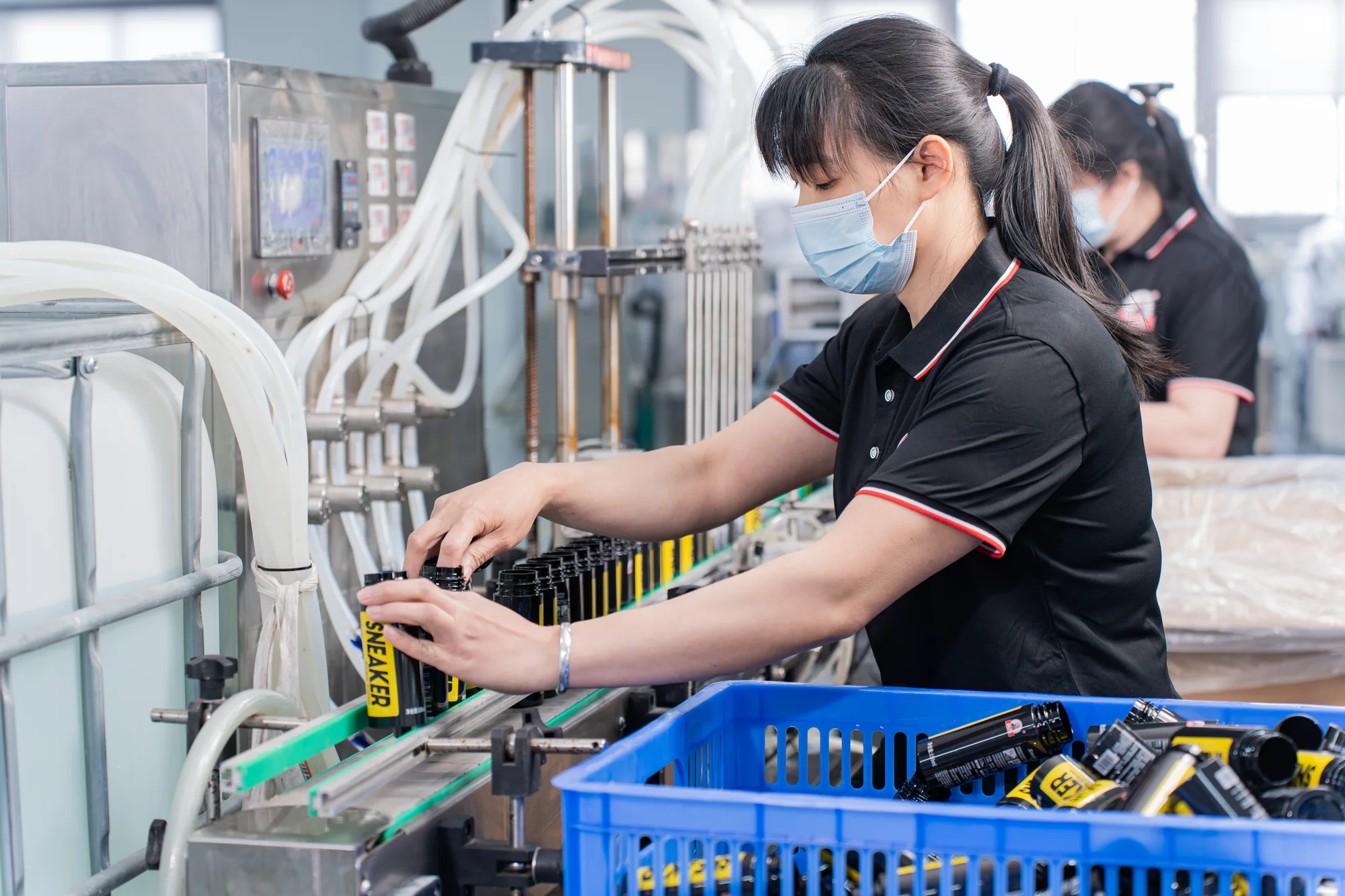 Workers filling household cleaning products on a factory line