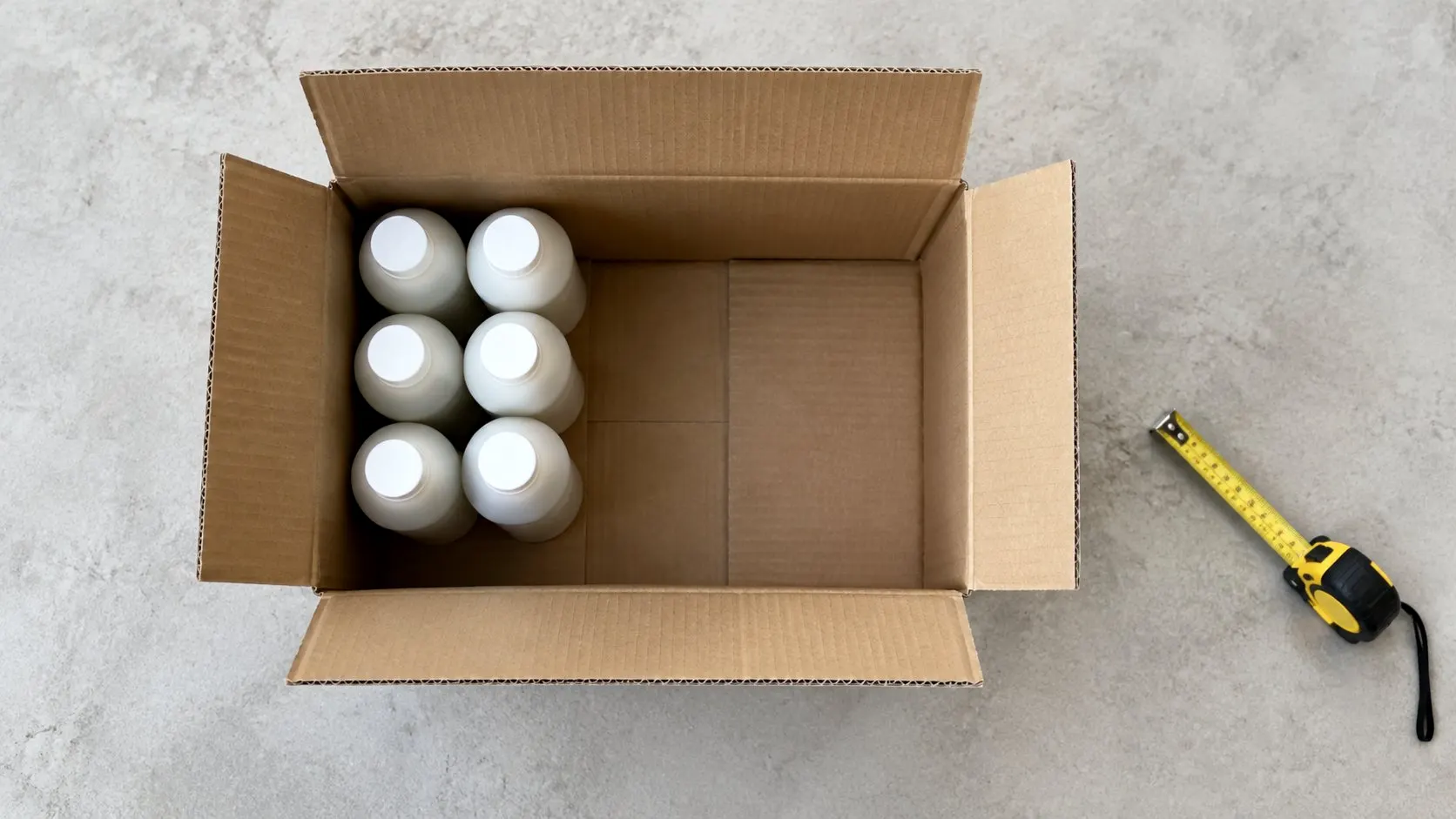 Open carton with six bottles in one corner and the rest empty, showing the PPWR 50 percent empty space limit